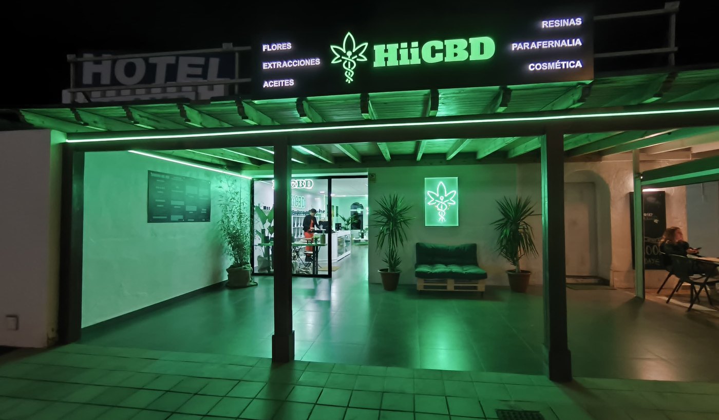 Tienda HiiCBD de Mojácar de noche, con el rótulo de neón encendido
